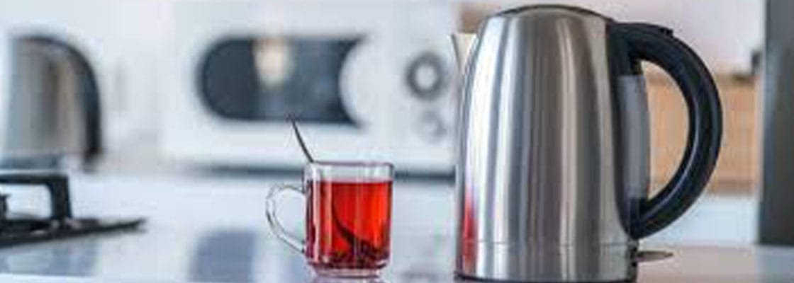 A stainless steel electric kettle and a cup of black tea