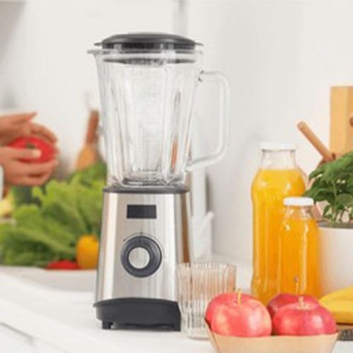 Blender with juice and apples on counter in kitchen, closeup