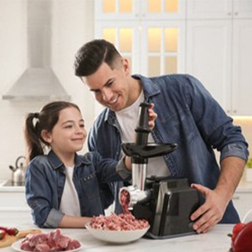 Father and daughter using modern meat grinder in kitchen. Space f