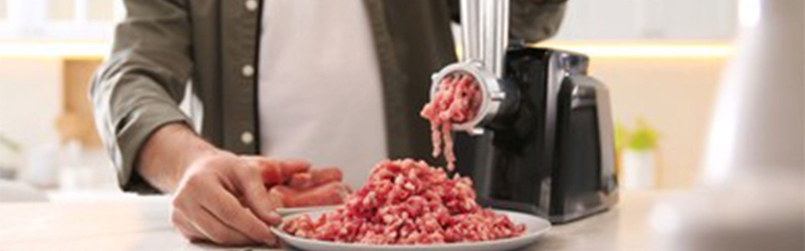 Man using modern meat grinder in kitchen, closeup