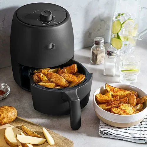 Black air fryer with potato wedges inside