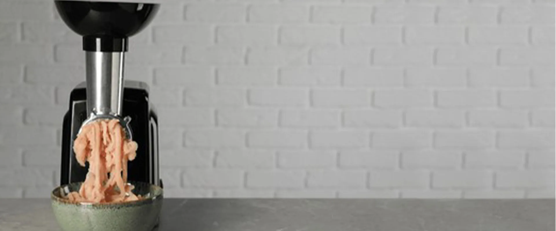 Mincing chicken with electric meat grinder on grey table. Banner